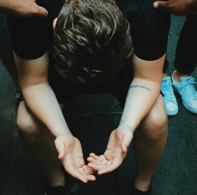 Young man praying, surrounded by peers