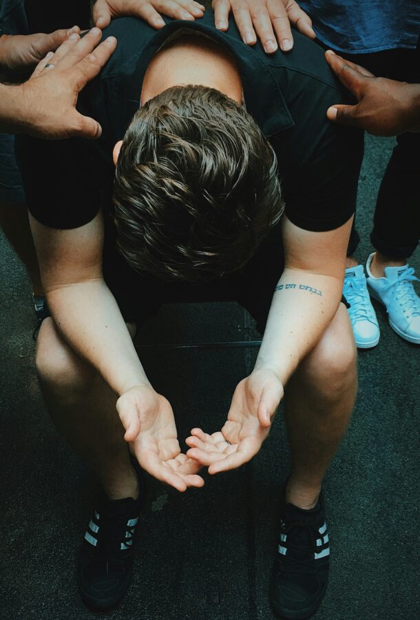 Young man praying, surrounded by peers