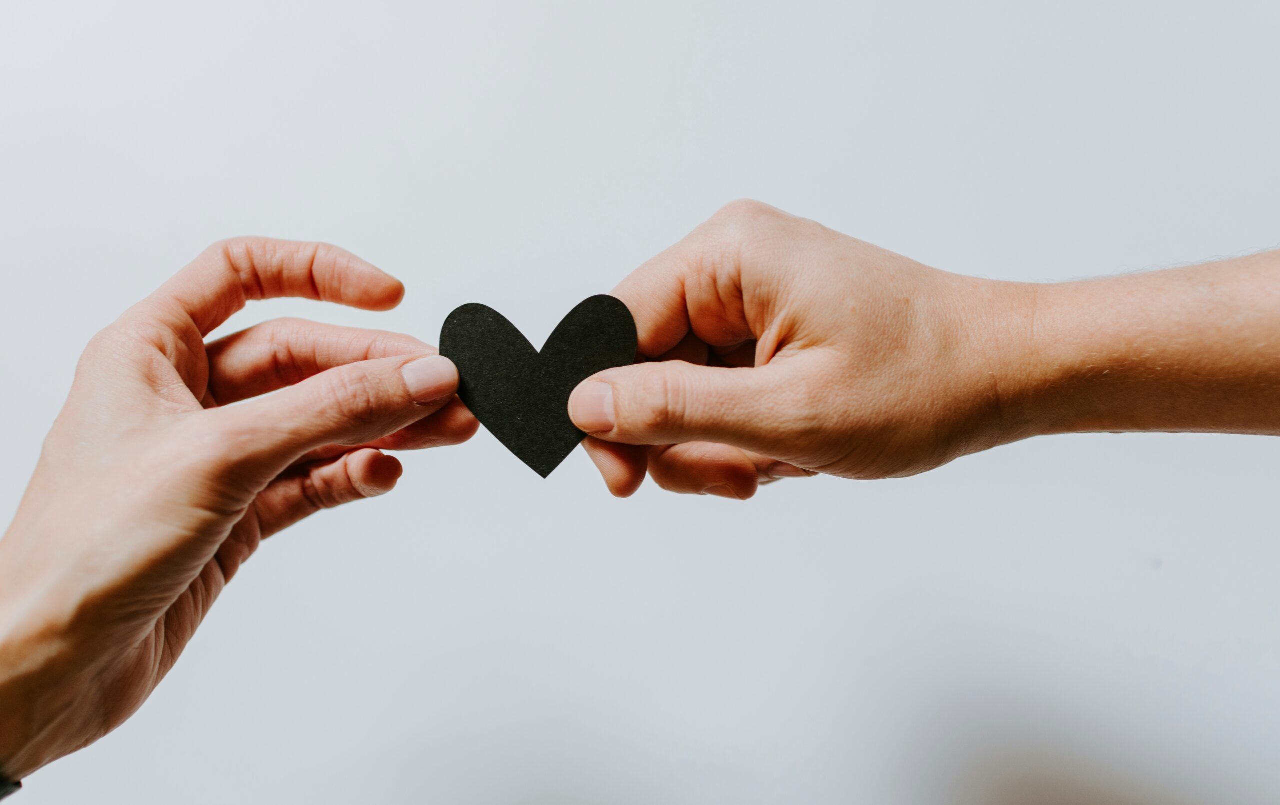 Two hands holding a heart together