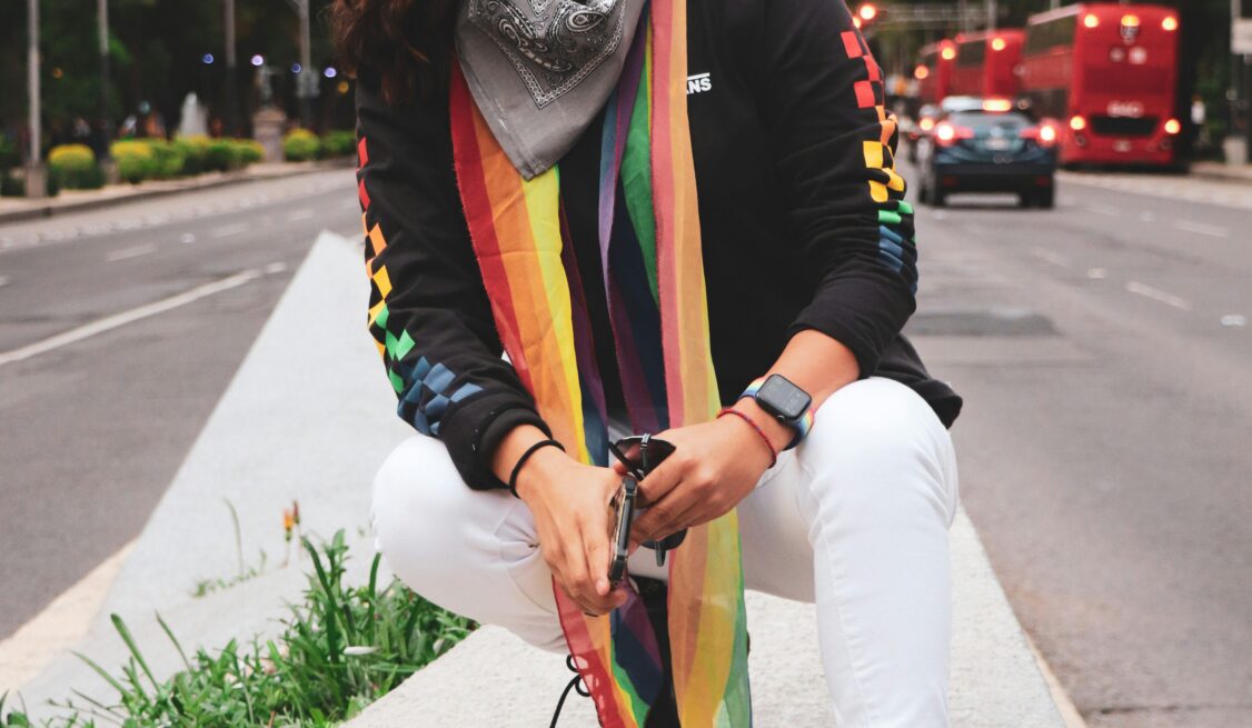 Gay black woman wearing a rainbow scar on the sidewalk